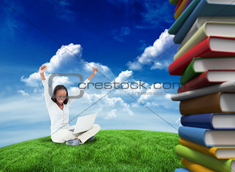 Composite image of young woman stretching while on the floor with her laptop