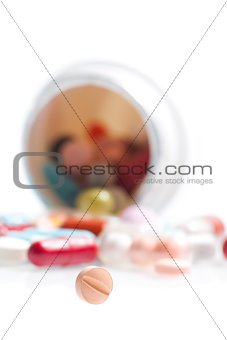 one small pill in laboratory in front of a colored pills
