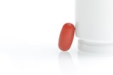 one red medical pill near white container
