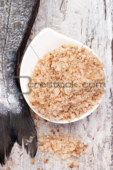 Seasalt in bowl and raw fish tail. Seafood background.