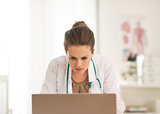 Concerned doctor woman looking in laptop