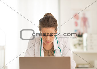 Concerned doctor woman looking in laptop