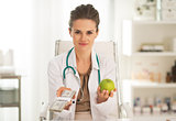 Doctor woman showing apple and pack of money
