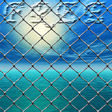 Freedom - Link fence over sunny sky and sea