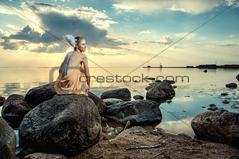 Young beautiful woman as swan posing on the beach at sunset