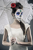 Day of the dead girl with sugar skull makeup holding lace umbrella