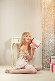 Sexy blond woman with a gift boxes posing indoors