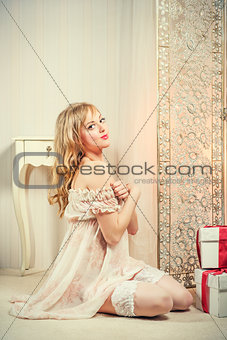 Sexy blond woman with a gift boxes posing indoors