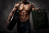 Muscular man with two metal fuel cans indoors