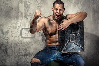 Muscular man with metal fuel can indoors