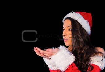 Pretty brunette in santa outfit blowing over her hands