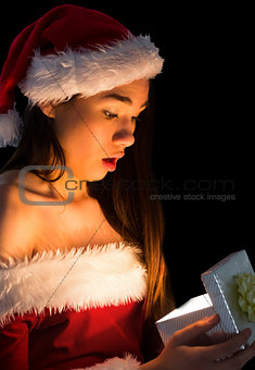 Amazed brunette in santa outfit opening a gift