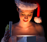 Pretty woman in santa outfit opening a gift smiling at it