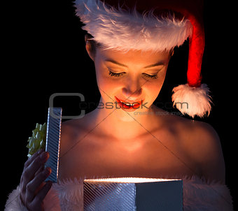 Pretty woman in santa outfit opening a gift smiling at it