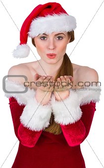 Pretty girl in santa costume blowing at camera