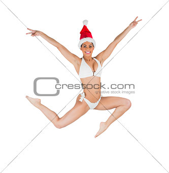 Fit girl in bikini smiling at camera wearing santa hat