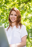Pretty redhead using her laptop in the park