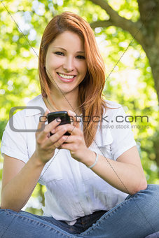 Pretty redhead sending a text in the park