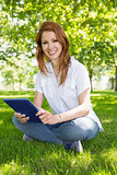 Pretty redhead using her tablet pc in the park