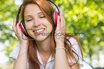 Pretty redhead listening to music in the park