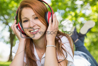 Pretty redhead listening to music in the park
