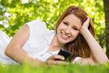 Pretty redhead lying on the grass sending a text