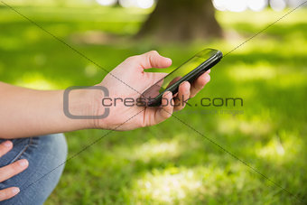 Woman sending a text on smartphone in the park