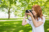 Pretty redhead taking a photo in the park