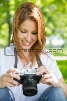 Pretty redhead looking at her camera in the park