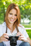 Pretty redhead holding her camera in the park