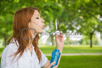 Pretty redhead blowing bubbles in the park