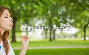 Pretty redhead blowing bubbles in the park