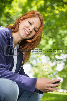 Pretty redhead relaxing in the park sending a text