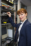 Pretty computer technician smiling at camera while fixing server