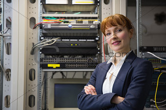 Pretty computer technician smiling at camera while fixing server