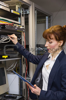 Pretty technician using tablet pc while fixing server
