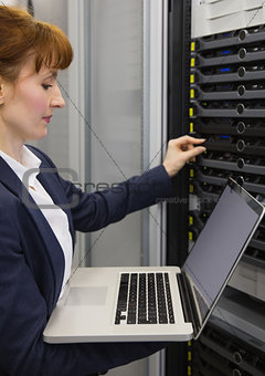 Pretty technician using laptop while working on servers