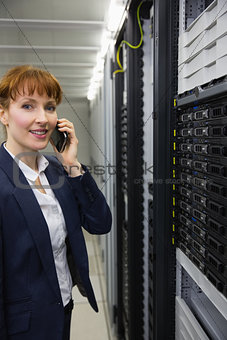 Smiling technician talking on phone while looking at server