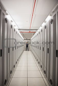 Serious technician standing in server hallway