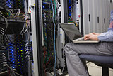 Technician sitting on swivel chair using laptop to diagnose servers