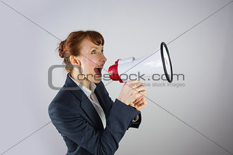 Smiling businesswoman shouting through megaphone
