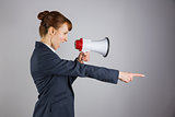 Angry businesswoman shouting through megaphone and pointing