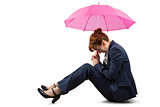 Sitting businesswoman holding pink umbrella