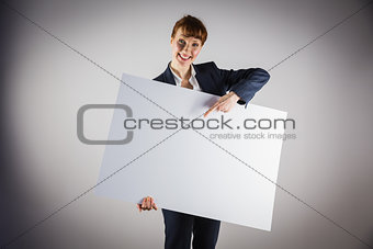 Smiling businesswoman holding and pointing to poster