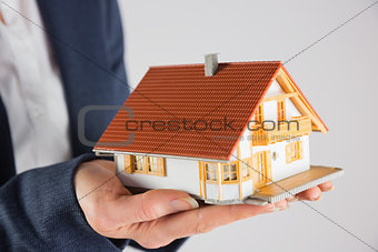 Businesswoman holding miniature model house
