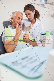 Patient showing dentist the problem in the mirror