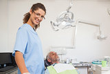 Dentist smiling at camera with patient in the chair