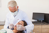 Dentist examining a patients teeth in the dentists chair