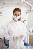 Dentist examining her tools on a tray looking at camera