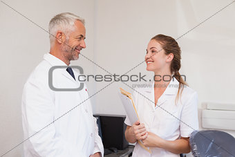 Dentist and dental assistant smiling at each other